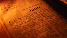 Focused close-up of the Bible's Gospel of John, highlighting sacred scriptures under warm light.